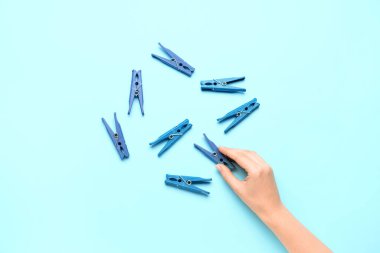 Mavi arka planda kadın eli ve plastik mandallar