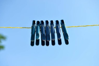 Mavi gökyüzüne karşı asılı plastik mandallar.