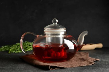 Koyu arkaplanda lezzetli kızılcık çayı olan çaydanlık.