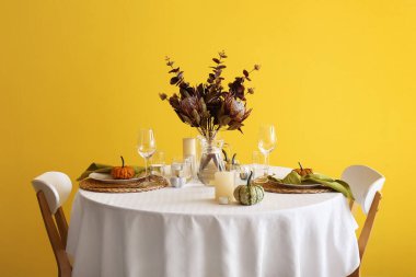 Taze balkabaklarıyla ve sarı duvarın yanında mumlarla güzel bir masa.