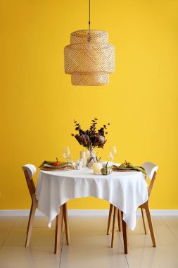 Taze balkabaklarıyla ve sarı duvarın yanında mumlarla güzel bir masa.