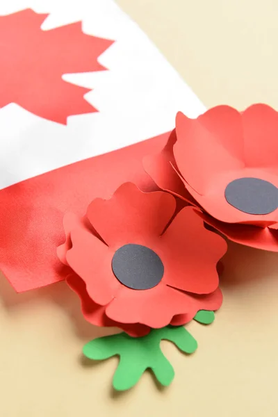 Paper poppy flowers with flag of Canada on color background, closeup. Remembrance Day