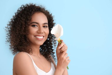 Mavi arka planda zambaklı genç Afro-Amerikalı kadın