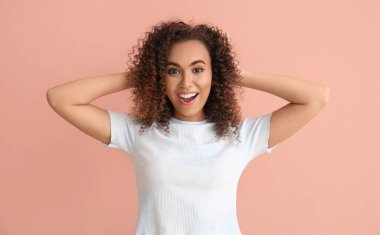 Pembe arka planda sağlıklı saçları olan genç Afro-Amerikalı kadın.