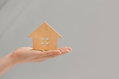 Ahşap evi ve gri arka planı olan bir kadın.