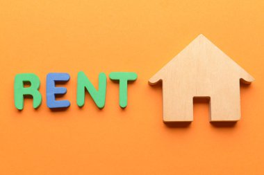 Ahşap ev ve turuncu arka planda kelime RENT