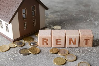 Kelime RENT ile ev modeli ve grunge arkaplanda madeni paralar