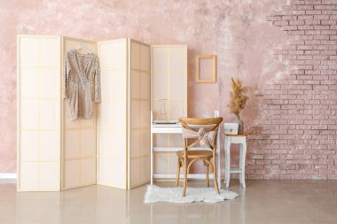 Masası ve katlanır ekranı olan şık bir odanın içi