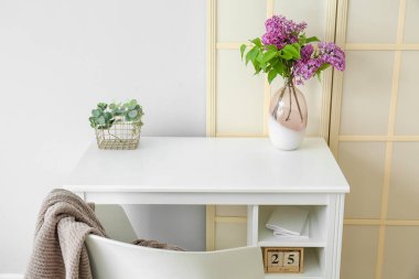 Vazoda leylak çiçekleri ve ışık duvarının yanında katlanan ekran.