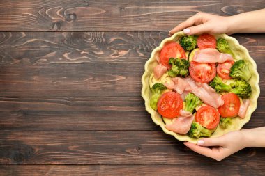 Ahşap arka planda pişmemiş tavuklu turta ile kadın elleri.