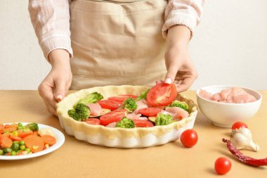 Mutfak masasında sebzeli tavuk turtası hazırlayan kadın, yakın plan.