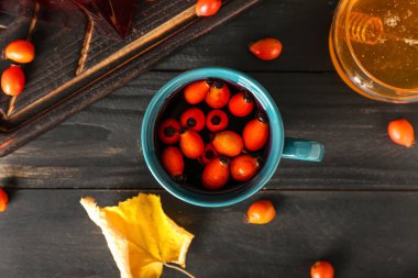 Siyah ahşap arka planda bir fincan lezzetli gül kalçası çayı.