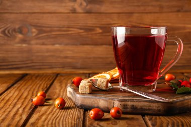 Ahşap zemin üzerinde bir bardak lezzetli gül kalçası çayı ve böğürtlen