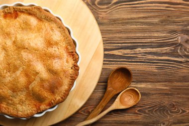 Ahşap arka planda lezzetli tavuklu turta pişirme tabağı, yakın plan.