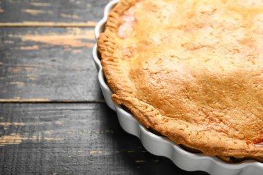 Ahşap arka planda lezzetli tavuklu turta pişirme, yakın plan.