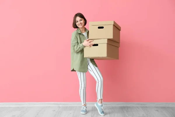 Young woman with wardrobe boxes near color wall