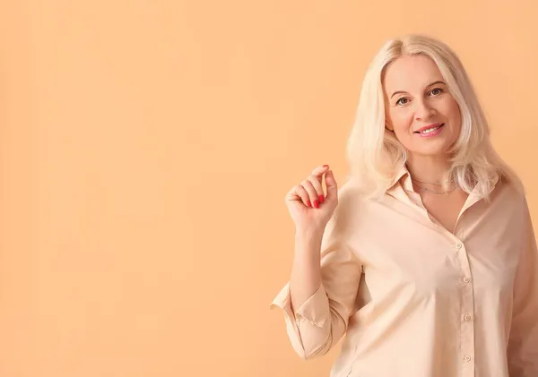 Beautiful Mature Woman Pointing Something Beige Background — Stock Photo, Image