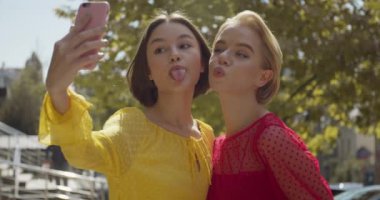 Güzel genç kadınlar dışarıda selfie çekiyorlar.