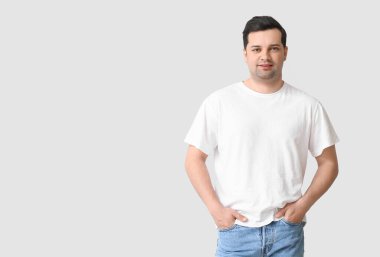 Hafif arka planda şık tişörtlü yakışıklı genç adam.