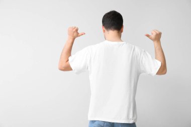 Hafif arka planda şık tişörtlü yakışıklı genç adam.