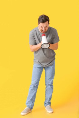 Renkli arka planda megafonu olan genç bir adamı protesto ediyor.