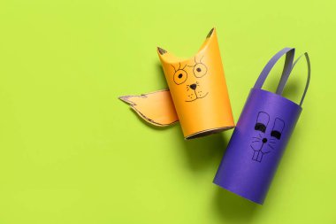 Yeşil arka planda tuvalet kağıdı için karton tüplerden yapılmış tavşan ve tilki figürleri