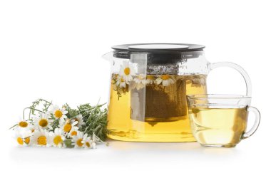 Çaydanlık ve bir fincan lezzetli çay ve beyaz arka planda papatya çiçekleri.