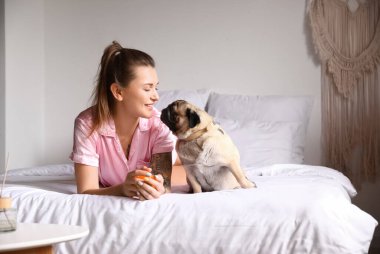 Tatlı köpeğiyle yatağa uzanmış genç bir kadın.