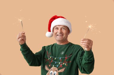 Noel Baba şapkalı olgun bir adam ve Noel havai fişekleri var.