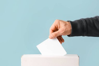 Renkli arka planda oy sandığının yanında oy veren adam