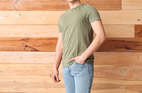 木製の背景にスタイリッシュなTシャツのハンサムな若い男 — ストック写真