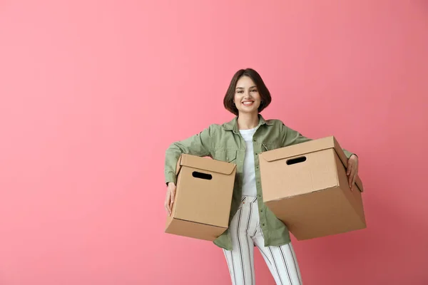 Young woman with wardrobe boxes on color background