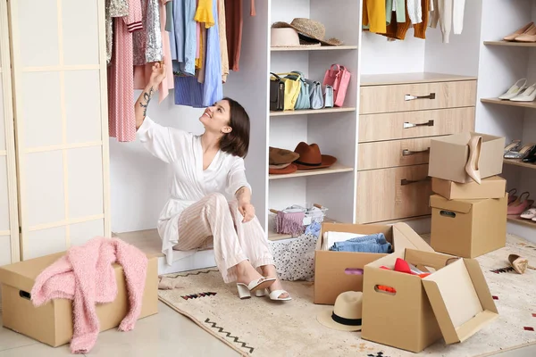 Genç bir kadın gardıropta kıyafet ayarlıyor.