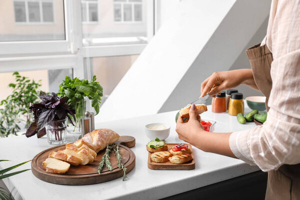 Woman spreading toast with dip at table in kitchen