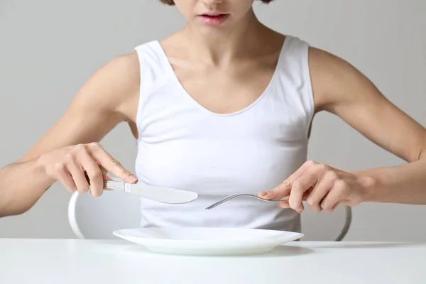 年轻的妇女与空盘子在桌子上 厌食症概念 — 图库照片