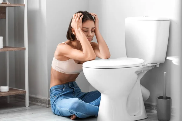 浴室里靠近马桶碗的年轻女人 厌食症概念 — 图库照片