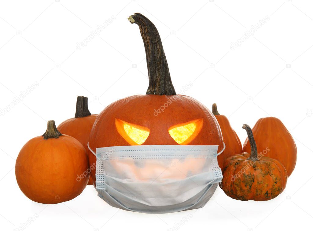 Carved and whole pumpkins for Halloween with medical mask on white background
