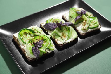 Yeşil arka planda lezzetli vejetaryen bruschetta tabağı, yakın plan.