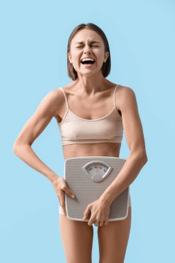 Arka planda ağırlık terazisi olan stresli bir kadın. Anoreksi kavramı