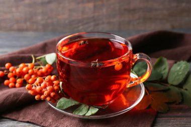 Tahta arka planda bir fincan sıcak yaban mersini ve çay.