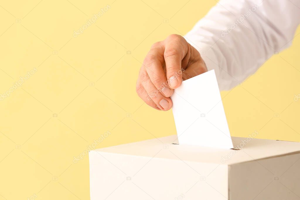 Voting man near ballot box on color background