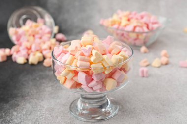 Gri arka planda leziz marşmelovlu cam kase, yakın plan.