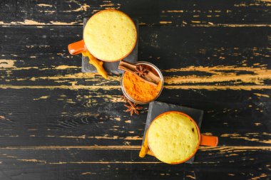 Sağlıklı ev yapımı, koyu ahşap arka planda baharatlı zerdeçal latte.