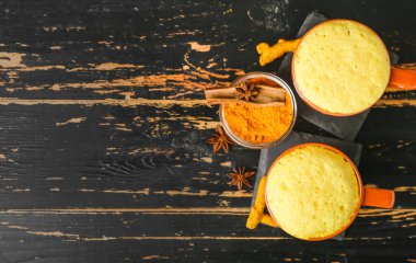 Koyu ahşap arka planda baharatlı sağlıklı zerdeçal latte.