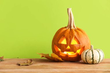 Yeşil arka planda Cadılar Bayramı için oyulmuş balkabakları.