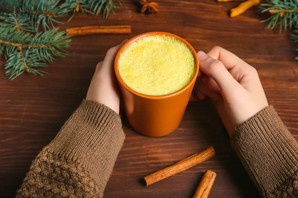 Female Hands Cup Tasty Turmeric Latte Cinnamon Fir Branches Wooden — Stock Photo, Image