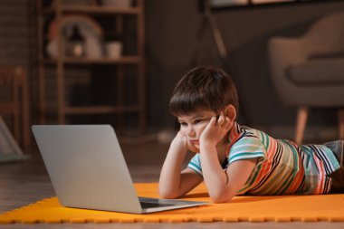 Küçük çocuk akşam geç saatlerde dizüstü bilgisayarında çizgi film izliyor.