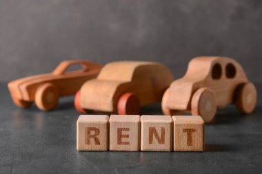 Kelime RENT siyah arka planda ahşap arabalar, yakın plan