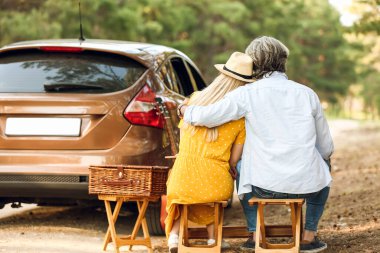 Dışarıda arabanın yanında sarılan mutlu, olgun bir çift.