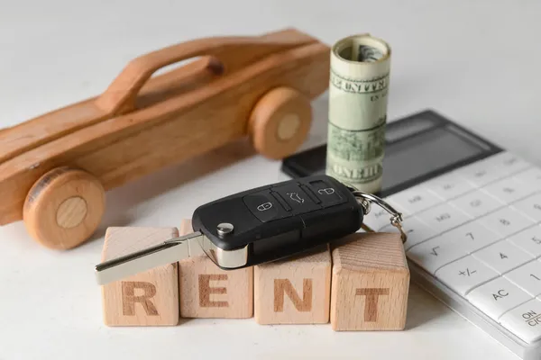 Word RENT with wooden car, key, money and calculator on white background